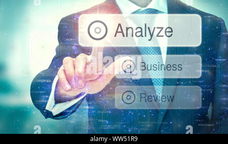 A businessman selecting a button on a futuristic display with a Analyze concept written on it. Stock Photo