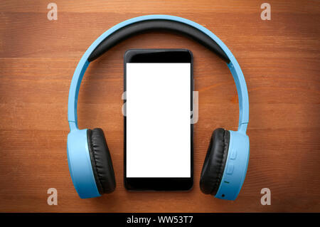 Blue headphones around a blank screen smartphone on orange wooden table Stock Photo