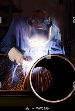 Worker welding pipe in workshop. Stock Photo