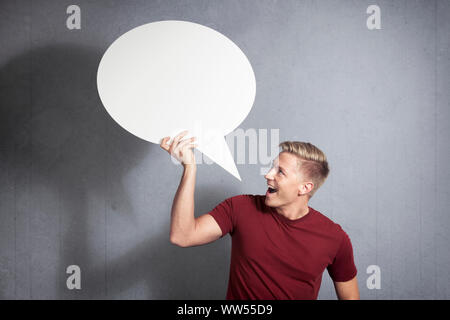 Joyous man holding empty speech balloon. Stock Photo
