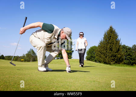 Golf player couple on green picking ball. Stock Photo