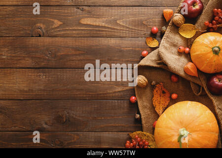 Harvest or Thanksgiving background with pumpkins, blanket, dried fall leaves, apples, red berries, walnuts on wooden table. Flat lay composition, top Stock Photo