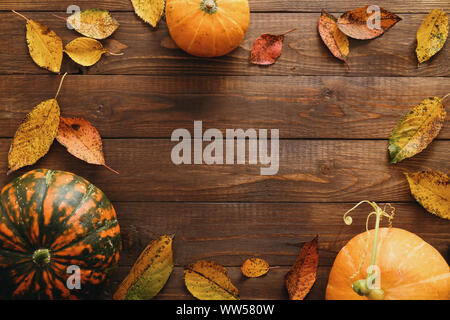 Harvest or Thanksgiving background with pumpkins and dried fall leaves on wooden table. Flat lay composition, top view, copy space Stock Photo