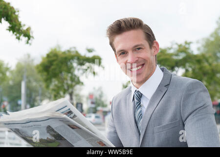 Man in grey sports jacket, reading newspaper, half portrait Stock Photo