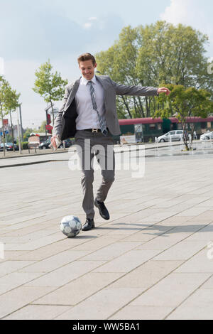 Man in grey suit, playing football Stock Photo