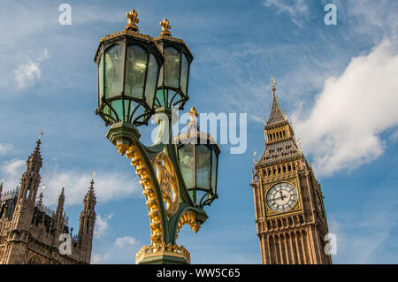 The Houses of Parliament and Big Ben with ornate street lamps on the Westminster Bridge in London in foreground.