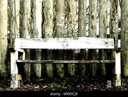 Front view on a park bench in front of a wall with round planks, Stock Photo