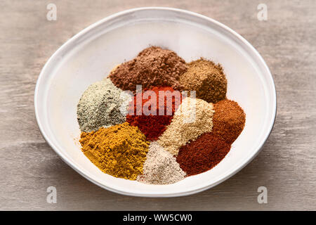 Different kind of spices in bowl for cooking on wooden background. Stock Photo