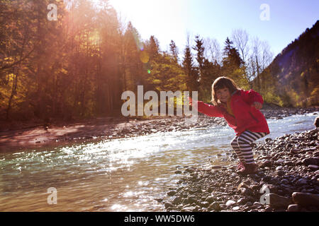 5-year-old girl in red jacket skipping stones Stock Photo
