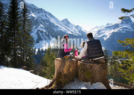 Father, mother and child having picnic on a trunk, view at mountain landscape Stock Photo