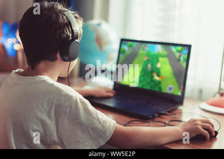 Little dependent gamer boy playing on laptop at home Stock Photo