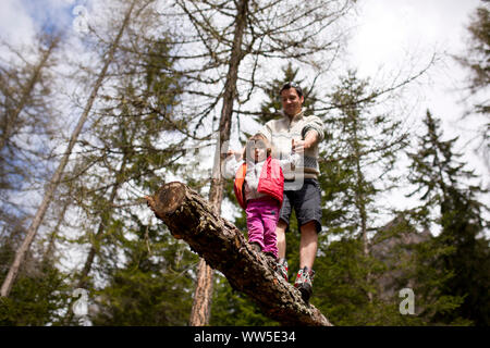 30-40 years old father balancingon a trunk in the forest with 4-6 years old daughter Stock Photo