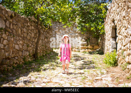 4-6 years old girl in pink outfit running along an old stony lane Stock Photo