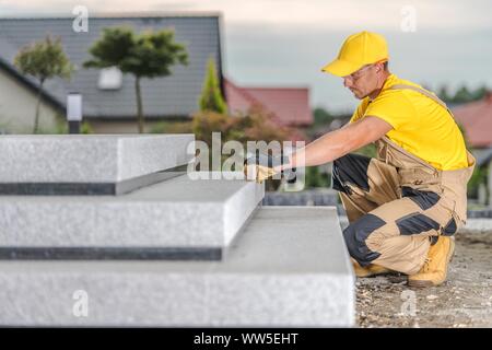 Concrete Stairs Building by Caucasian Construction Contractor Worker. Checking Levels. Industrial Theme. Stock Photo