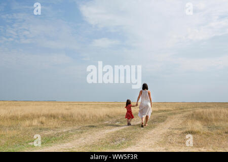 30-40 years old mother with 4-6 years old child walking hand in hand on a country lane Stock Photo