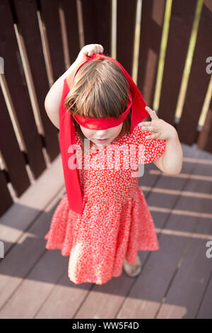 4-6 years old girl in red dress and red blindfold Stock Photo