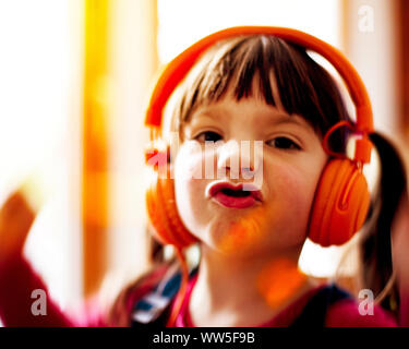 4-6 years old child dancing with orange headphones, facial play, portrait Stock Photo