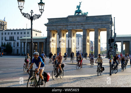 28.08.2019, Berlin, Germany: cyclists in rush hour on the square of the 18th March in front of the Brandenburg Gate in the morning with low sun in the Stock Photo