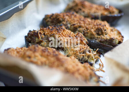 Aubergine stuffed au gratin with meat and cheese from above on a white wooden table of a rustic kitchen. Stock Photo