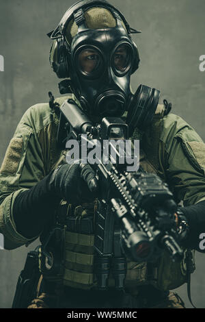 Special unit soldier with gasmask and tactical equipment is holding assault rifle Stock Photo