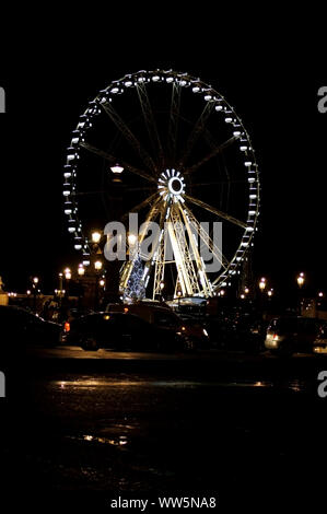 The night photography of a Ferris Wheel on the Place de la Concorde with traffic in the foreground in Paris,