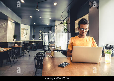 Handsome and successful indian man freelancer work laptop in cafe. Freelance and remote work. Stock Photo