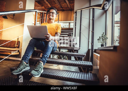 Smiling modern young man using gadgets at cafe. The concept of study, freelancing, work, technology. Stock Photo