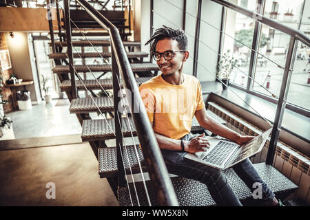 Young indian man sitting in coffeeshop table and working on laptop. The concept of study, freelancing, work, technology Stock Photo