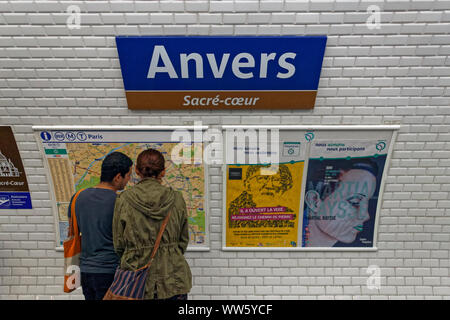 France, Paris, man, woman, metro route map, advertisement, station sign, Anvers, SacrÃ©-CÅ“ur Stock Photo