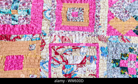textile background - geometric ornament of patchwork scarf stitched from various silk strips and crushed pink cotton fabric Stock Photo