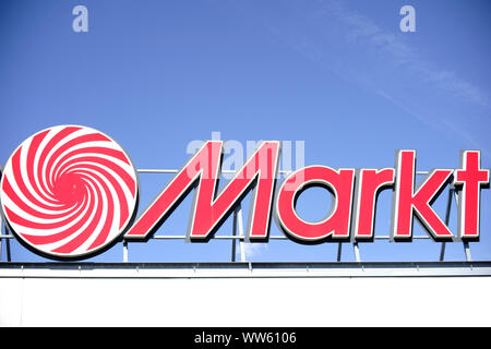 The red bright company sign of the electronics and hifi market Media Markt on the roof edge of a facade,