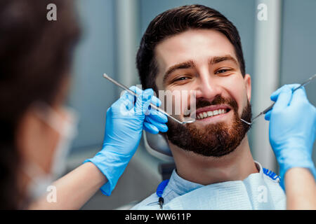 Female dentists working on young male patient. selective focus. Close up view. Stock Photo