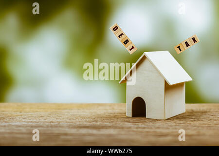 Home taxes and debt concept. A small house model on wooden table with a problem over the roof with space for text. Depicts a problems and liabilities Stock Photo