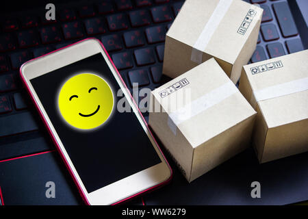 Conceptual the customer responded to the survey. The happy face smile icon  in smartphone after shopping online. Depicts that customer is very satisfi Stock Photo