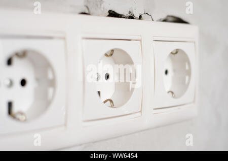 Electric EU socket outlet on gray concrete wall background. Repair in an apartment or in office, replacement of electrical wiring. Close up view. Stock Photo