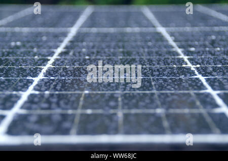 Photovoltaic solar energy panels in the rain. Water raindrops on cell glass. Stock Photo