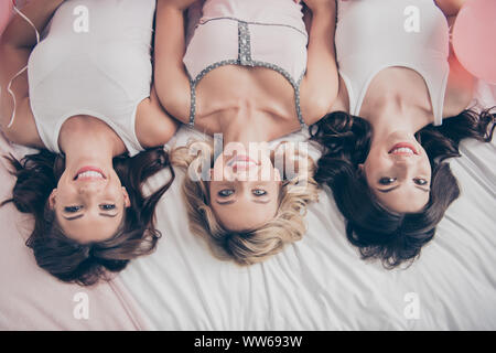 Top above high angle view of nice cute lovely winsome attractive feminine charming cheerful cheery caucasian girlfriends having fun lying on bed in Stock Photo