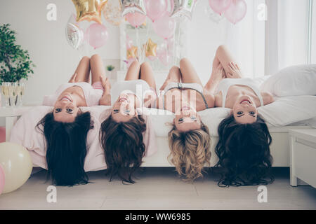 Nice cute gorgeous winsome lovely attractive cheerful cheery caucasian dreamy girlfriends having fun lying on bed in light white interior decorated Stock Photo