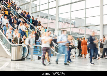 Many anonymous people on escalator and stairs of a trade fair Stock Photo