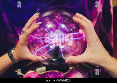 Hand touching a plasma ball with smooth magenta-blue flames. Stock Photo