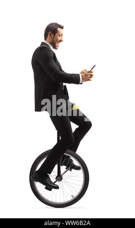 Full length shot of a businessman riding a unicycle and typing on a mobile phone isolated on white background Stock Photo