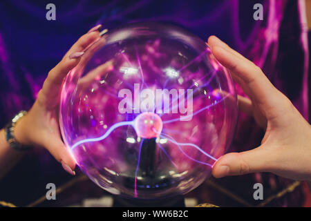 Hand touching a plasma ball with smooth magenta-blue flames. Stock Photo