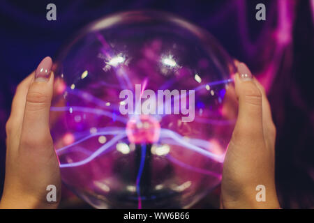 Hand touching a plasma ball with smooth magenta-blue flames. Stock Photo