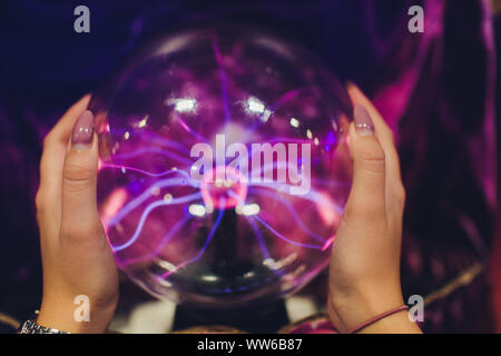 Hand touching a plasma ball with smooth magenta-blue flames. Stock Photo