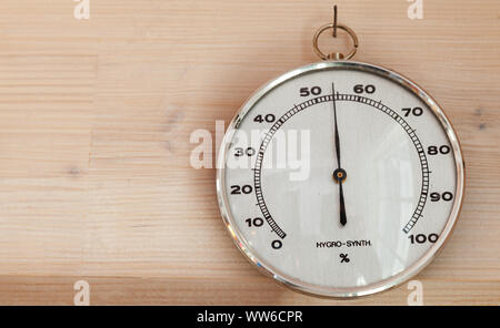Hygrometer hanging on wooden wall, close-up photo. This instrument used to measure the amount of humidity and water vapour in the atmosphere Stock Photo