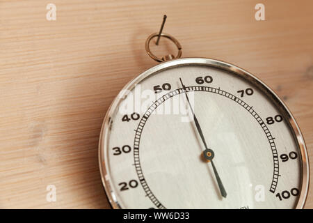 Analog hygrometer hanging on wooden wall, close-up photo. This hair tension instrument used to measure the amount of humidity and water vapour in the Stock Photo