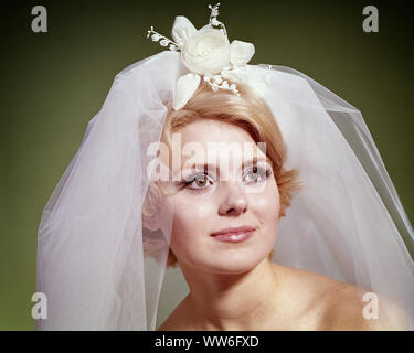 1960s 1960s PORTRAIT OF BLONDE BRIDE WEARING NET VEIL WITH WHITE FLORAL ACCESSORY LOOKING OFF TO THE SIDE - kb6703 HAR001 HARS CUSTOM TRADITION NUPTIAL NUPTIALS OCCASION MARRYING PRIDE ACCESSORY STILL LIFE RITE OF PASSAGE STYLISH WED BROWN EYES MARRY MATRIMONY YOUNG ADULT WOMAN CAUCASIAN ETHNICITY HAR001 OLD FASHIONED Stock Photo
