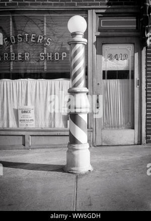 1950s OLD FASHIONED ADVERTISING ILLUMINATED ROTATING BARBER POLE WITH GLASS GLOBE ON SIDEWALK  IN FRONT OF BARBER SHOP - q52016 CPC001 HARS OLD FASHIONED Stock Photo