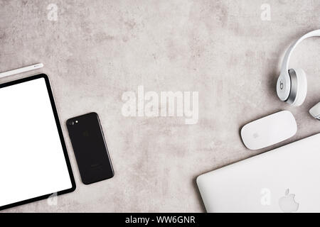 ZAGREB, CROATIA - SEPTEMBER 10, 2019: Top view on workplace. Apple iPad Pro, iPhone, MacBook Pro and Beats headphone on grey concrete background. Flat Stock Photo