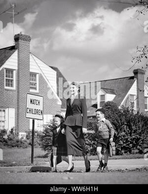 1940s 1950s SMILING WOMAN MOTHER WEARING SUIT WALKING TWO CHILDREN BOY GIRL TO SCHOOL CROSSING STREET BY WATCH CHILDREN SIGN - s4006 HAR001 HARS SUBURBAN MOTHERS OLD TIME NOSTALGIA BROTHER CROSSING OLD FASHION SISTER 1 JUVENILE ELEMENTARY STYLE YOUNG ADULT SAFETY SONS FAMILIES LIFESTYLE FEMALES HOUSES BROTHERS HOME LIFE COPY SPACE FULL-LENGTH LADIES DAUGHTERS PERSONS RESIDENTIAL CARING MALES BUILDINGS SIBLINGS SISTERS B&W SCHOOLS GRADE ADVENTURE PROTECTION STRENGTH STYLES LOW ANGLE PRIDE HOMES PRIMARY SIBLING CONNECTION RESIDENCE STYLISH K-12 COOPERATION FASHIONS GRADE SCHOOL JUVENILES MOMS Stock Photo